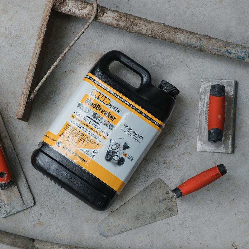 Jug of 'Mud Breaker' on a concrete surface with construction tools around