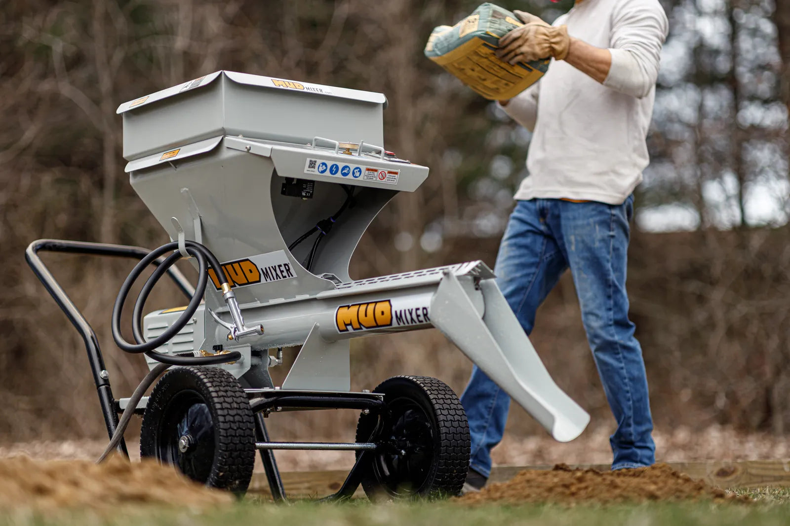 Contractor loading a bag of concrete into a MudMixer